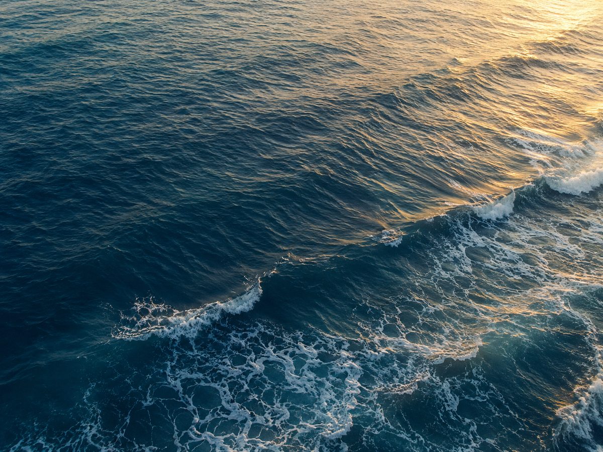 The Mediterranean seen from above at golden hour, waves in constant motion